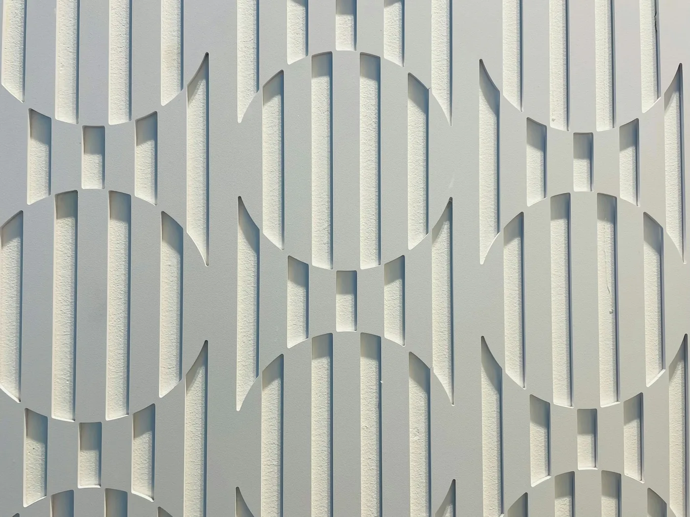 A white 3D wall panel with a wave relief lit from above