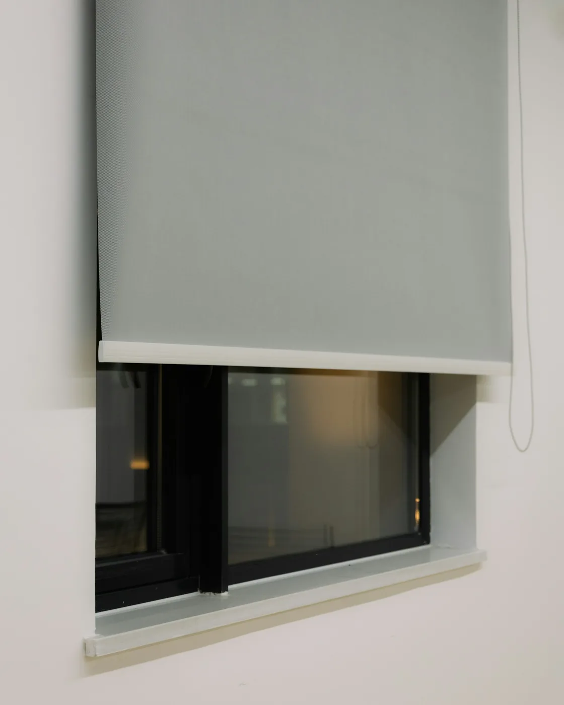A blackout roller blind pulled down over a bedroom window