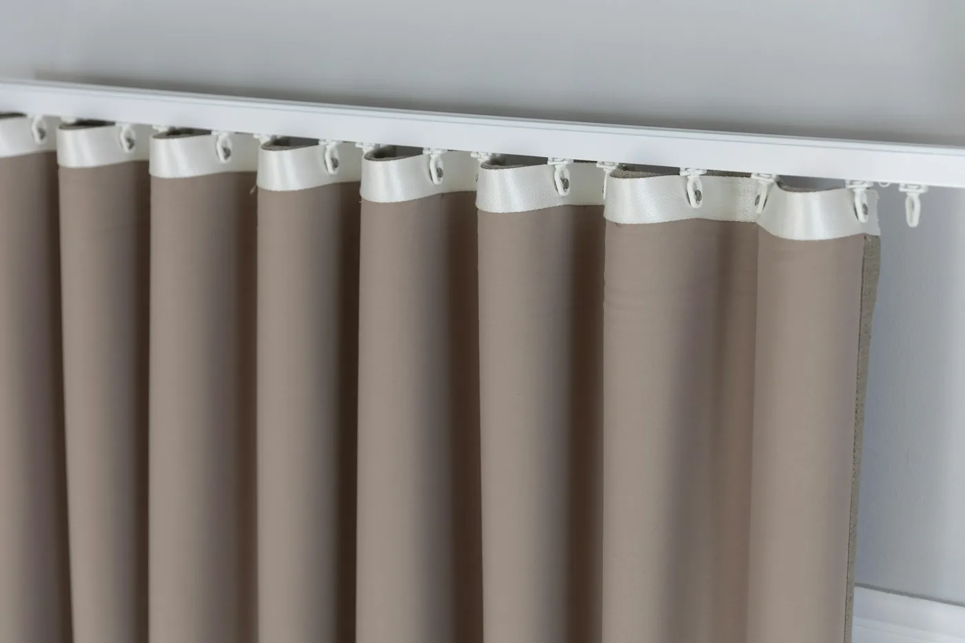 An aluminium curtain track with gliders and hooks fixed above a window