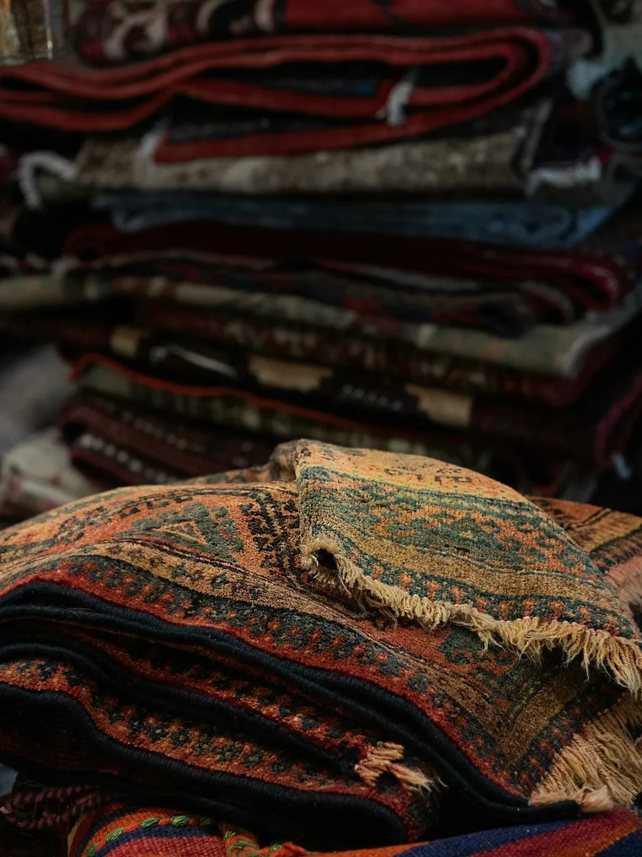 A stack of colourful flat-woven rugs and dhurries