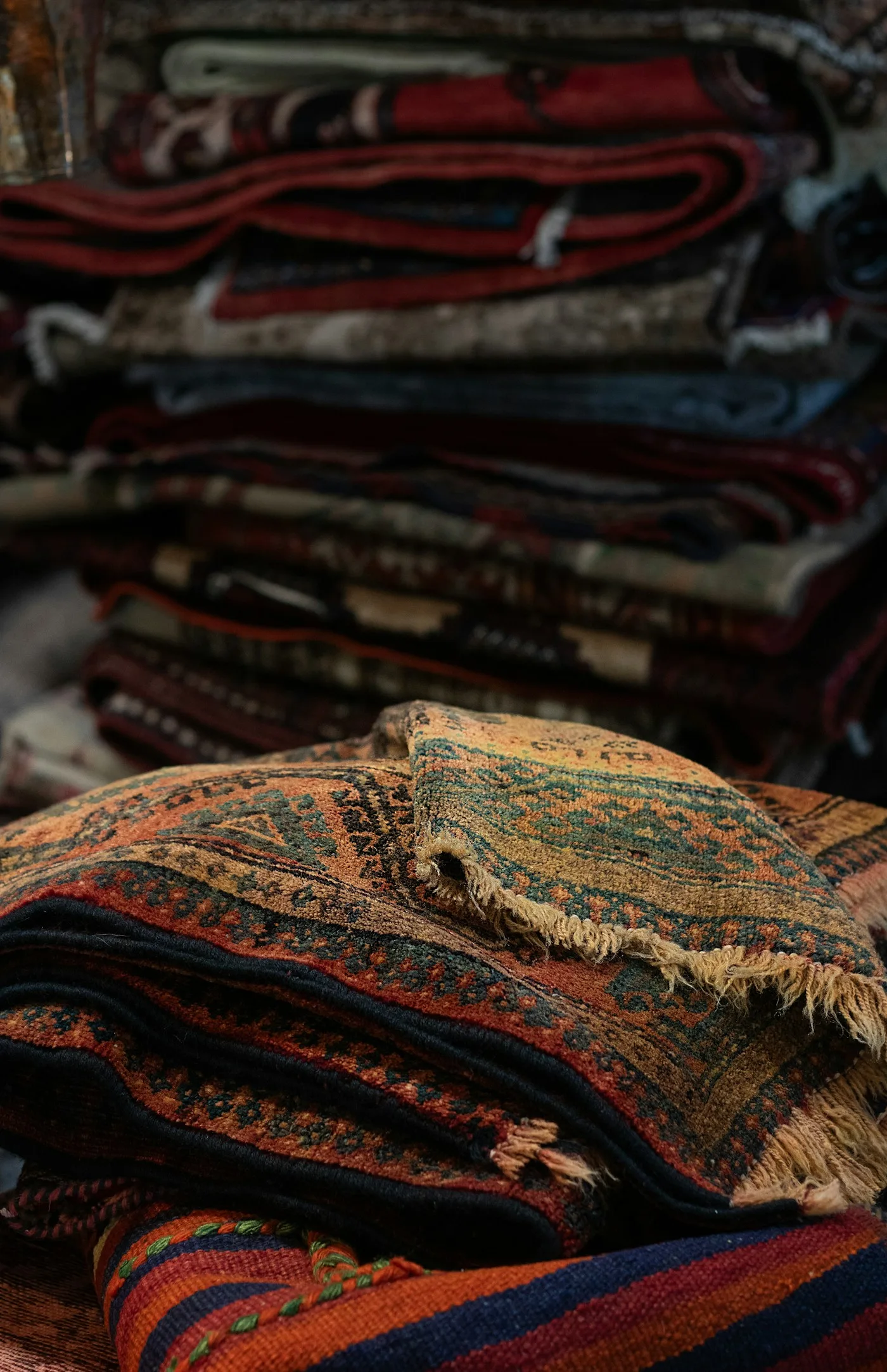 A stack of colourful flat-woven rugs and dhurries