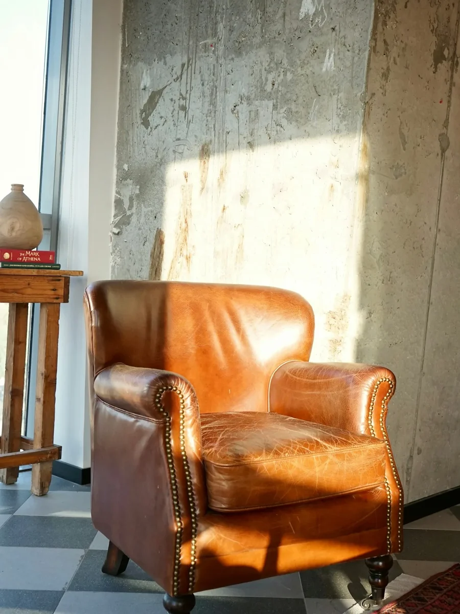 A tan leather armchair in warm sunlight on a patterned floor