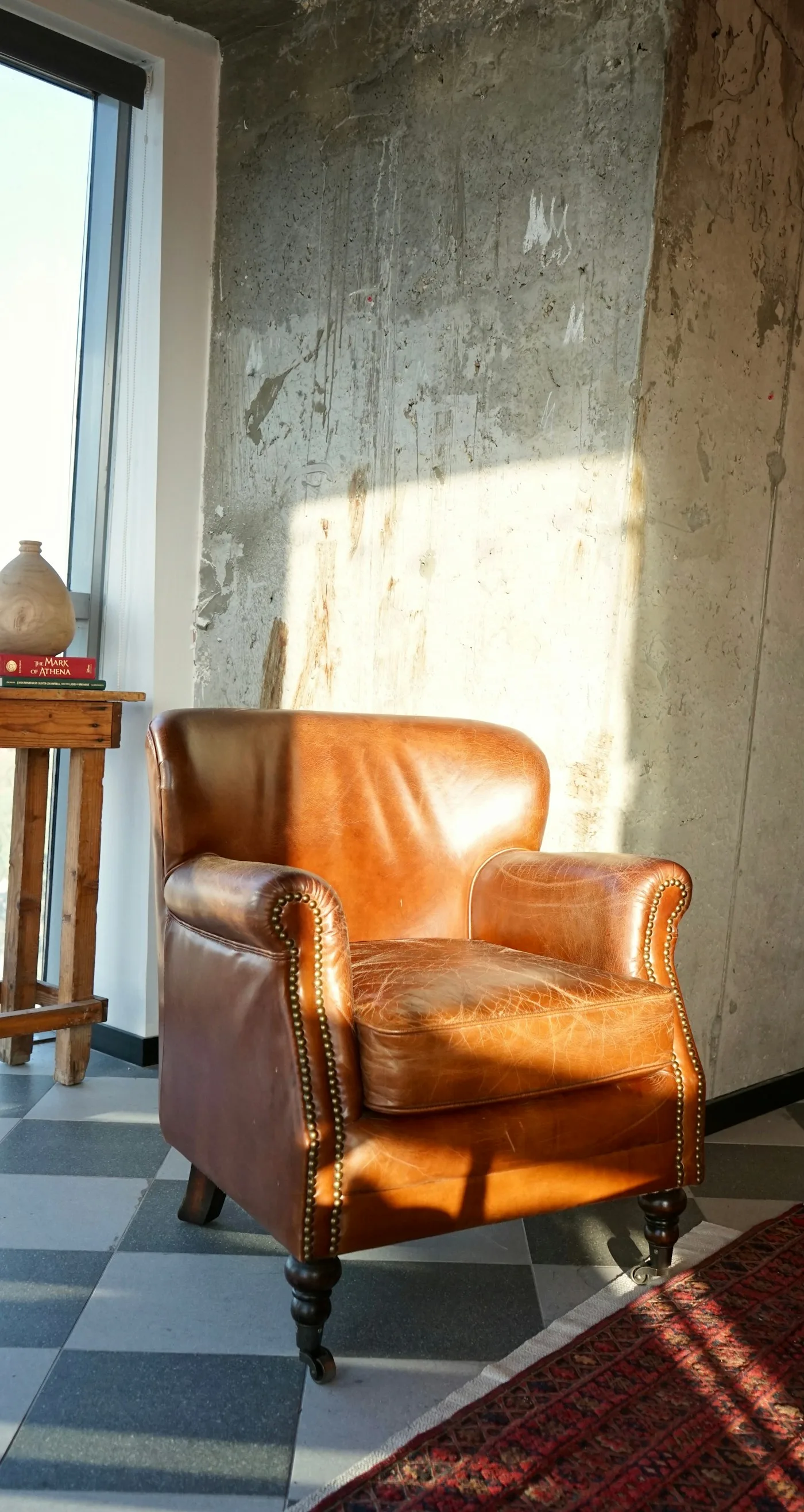 A tan leather armchair in warm sunlight on a patterned floor