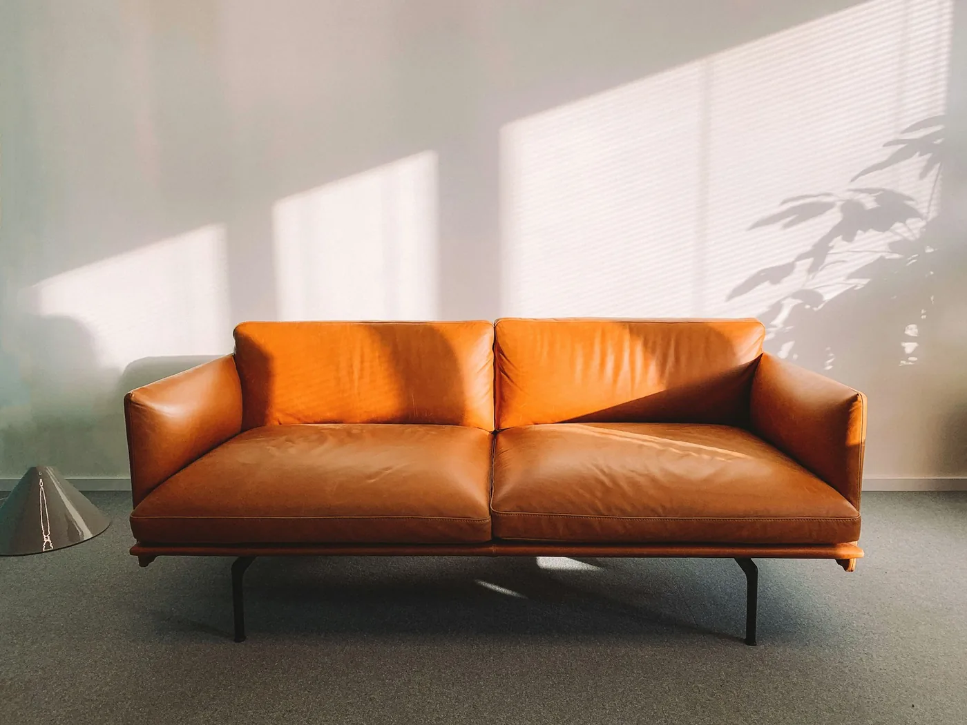 A brown leather sofa with a tight back and seat cushions in a bright living room