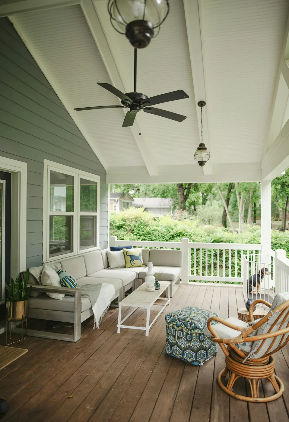 An outdoor sofa with light cushions on a covered verandah beside a garden