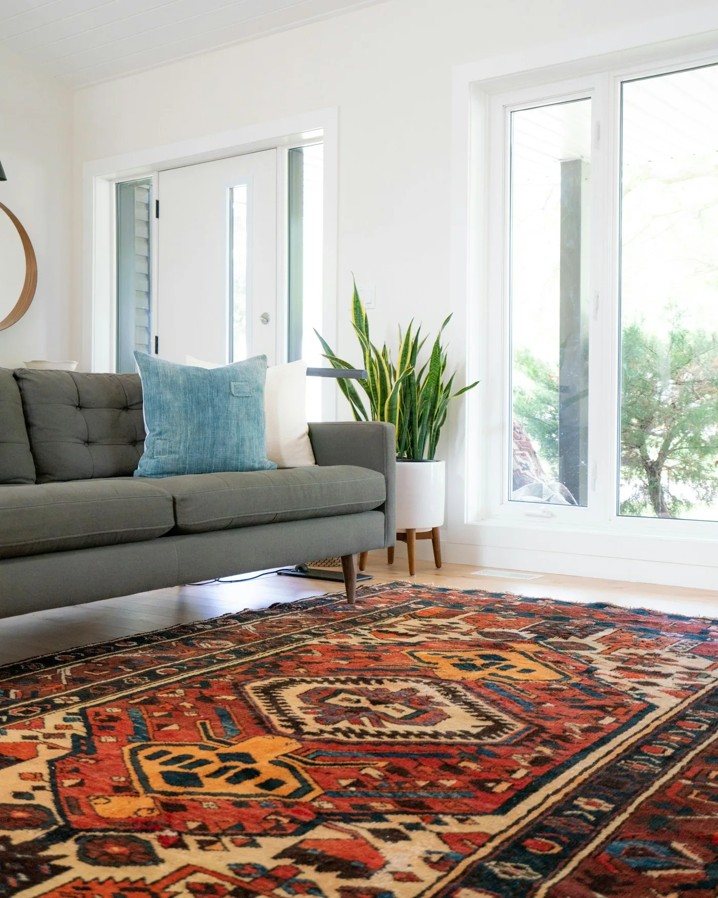 A red hand-knotted rug in a bright living room with a grey sofa