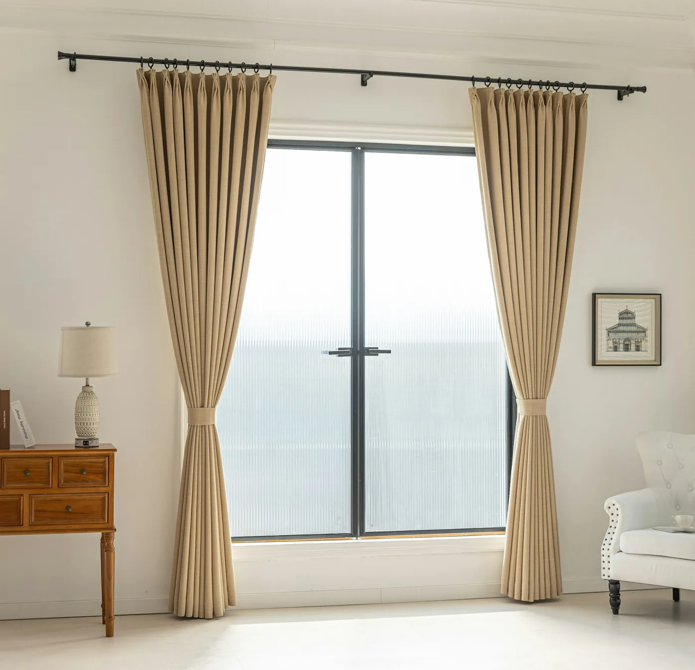 Pinch pleat curtains hanging in tailored folds from a ceiling track beside a tall window