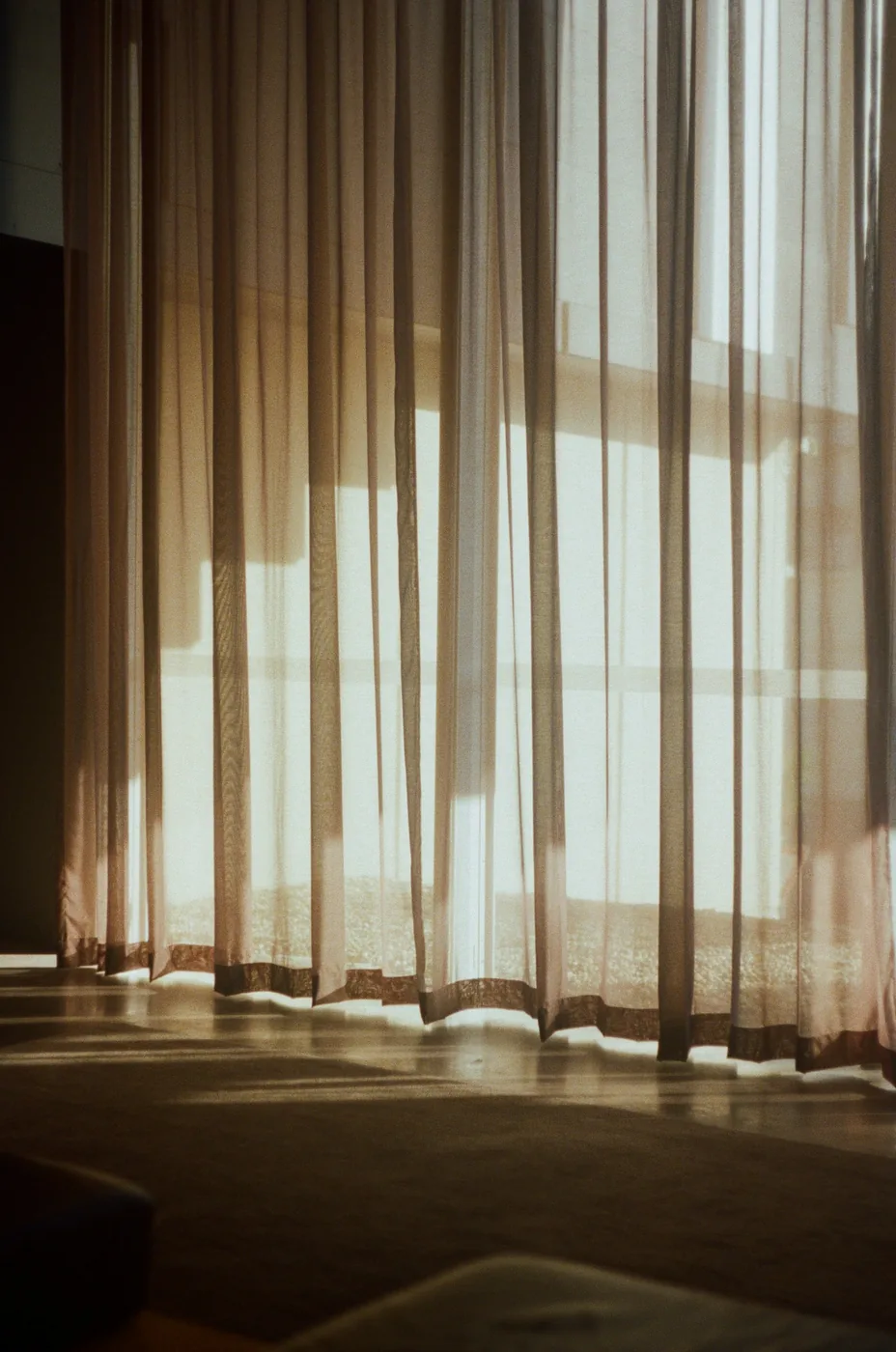 Ripple-fold curtains on a ceiling track across a wide glass wall