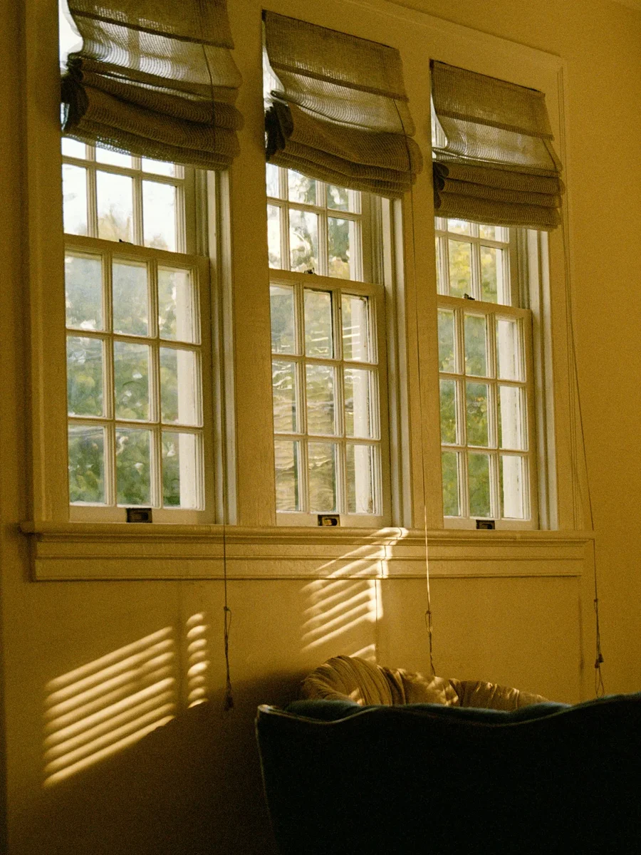 Fabric Roman blinds on three tall windows in warm afternoon light