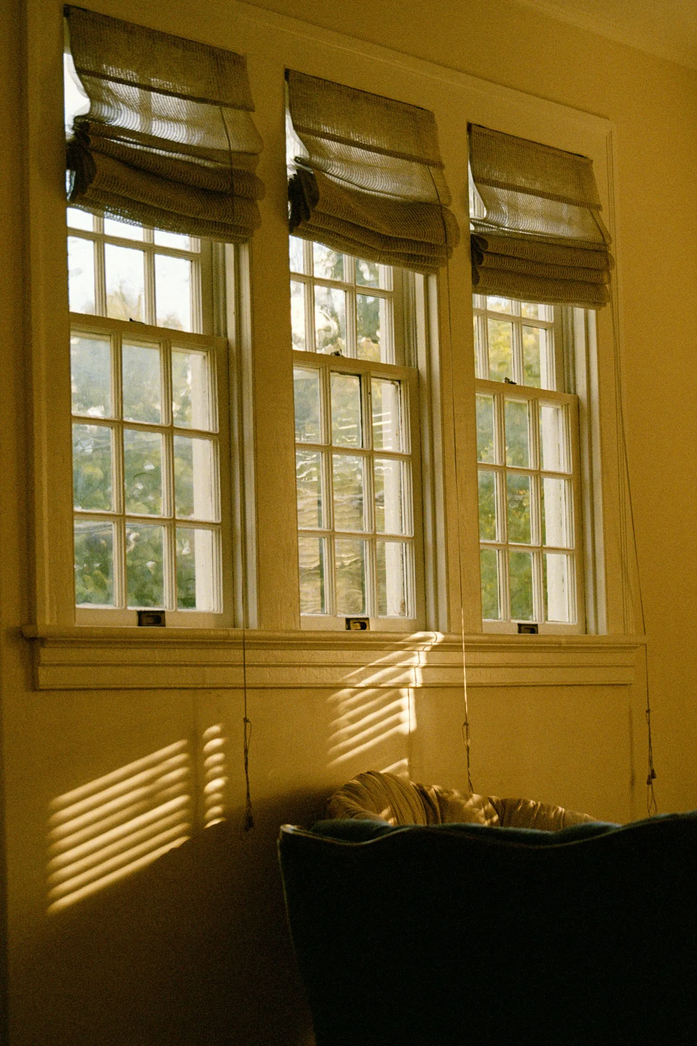 Fabric Roman blinds on three tall windows in warm afternoon light