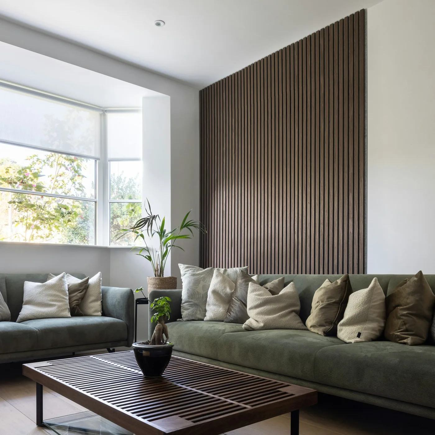 A living room wall finished in wall panels behind a low sofa