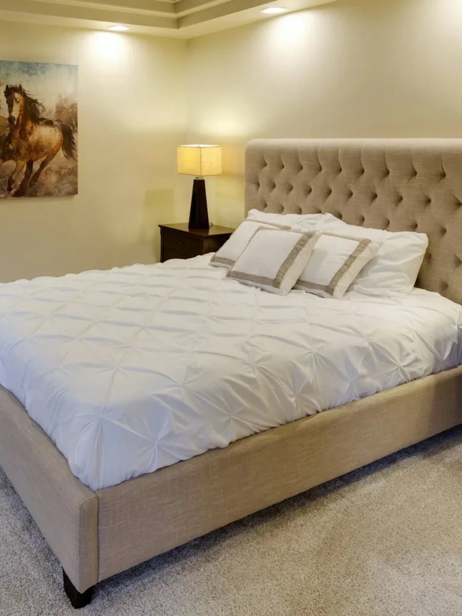 A bedroom with soft wall-to-wall carpet and an upholstered bed