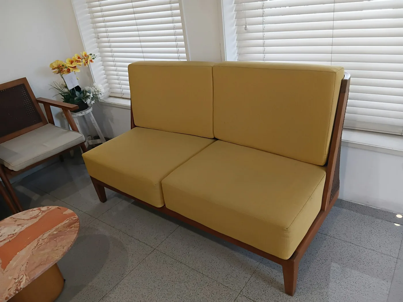 A wooden sofa with carved arms and loose seat cushions in a living room