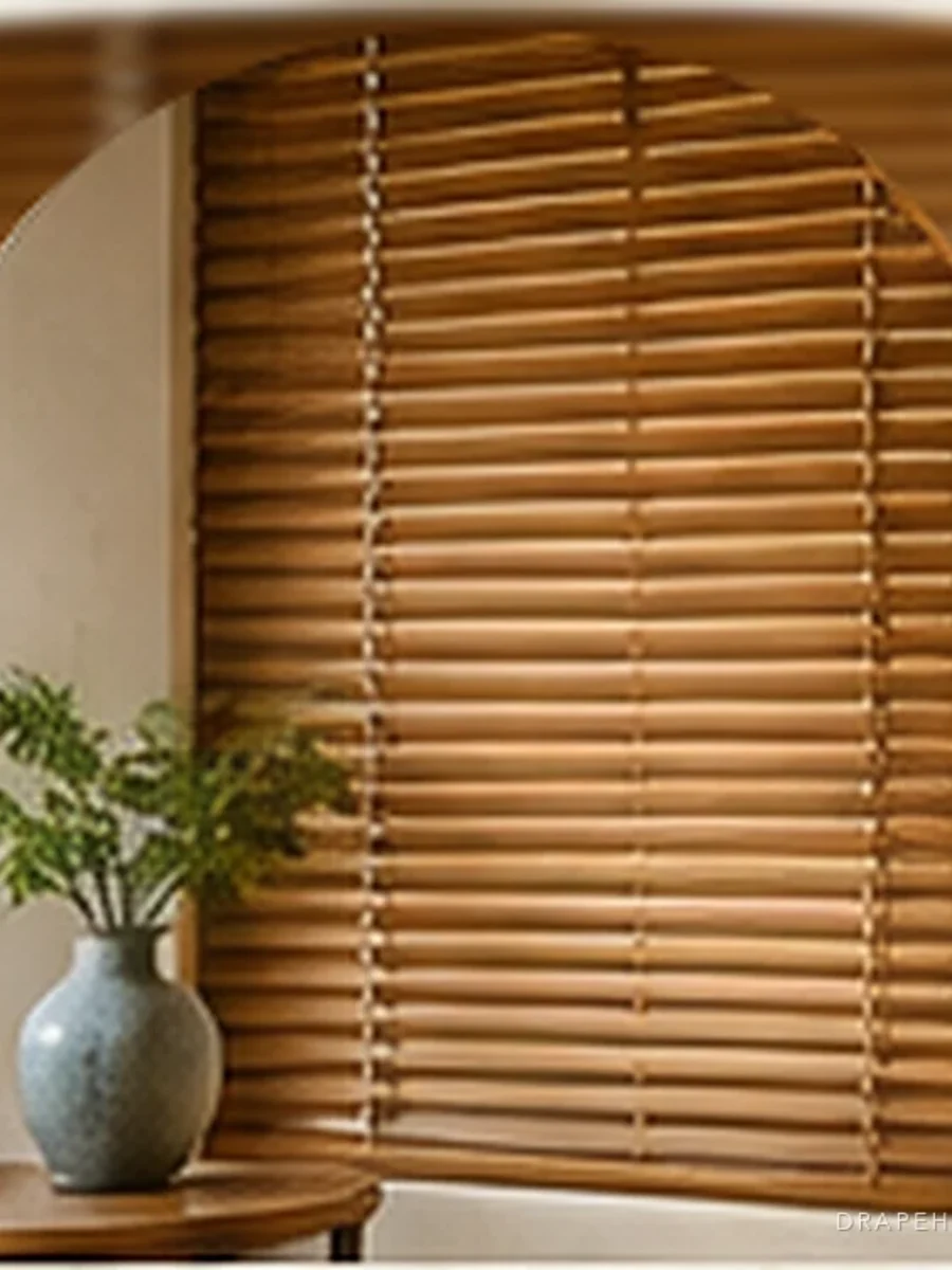 Wooden Venetian blinds beside a glazed vase and a potted fern