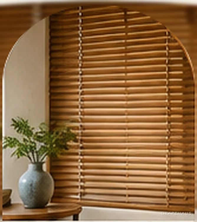 Wooden Venetian blinds beside a glazed vase and a potted fern
