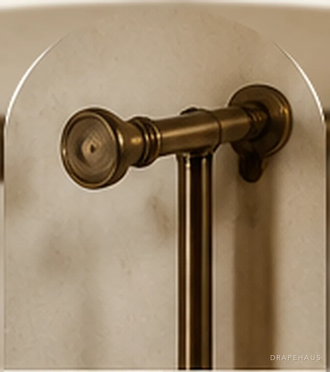 An antique brass curtain pole and finial on a lime-plastered wall