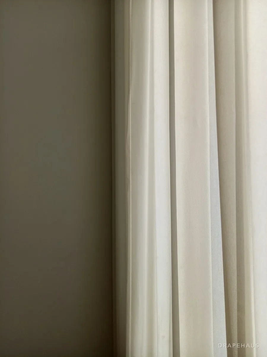 Soft cotton curtains hanging in folds beside a window