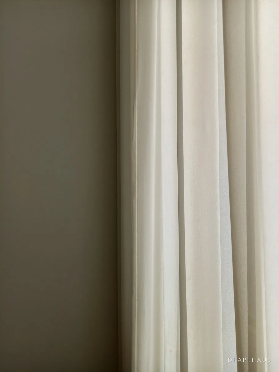 Soft cotton curtains hanging in folds beside a window
