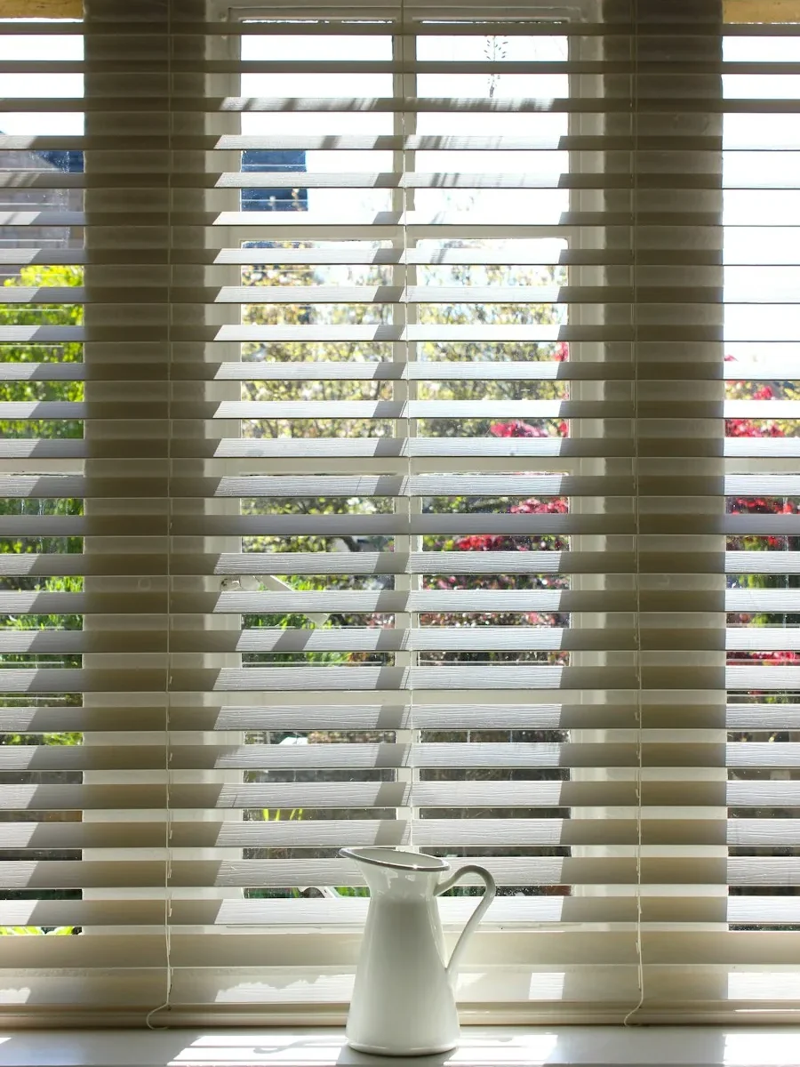 White faux-wood Venetian blinds on a bright window