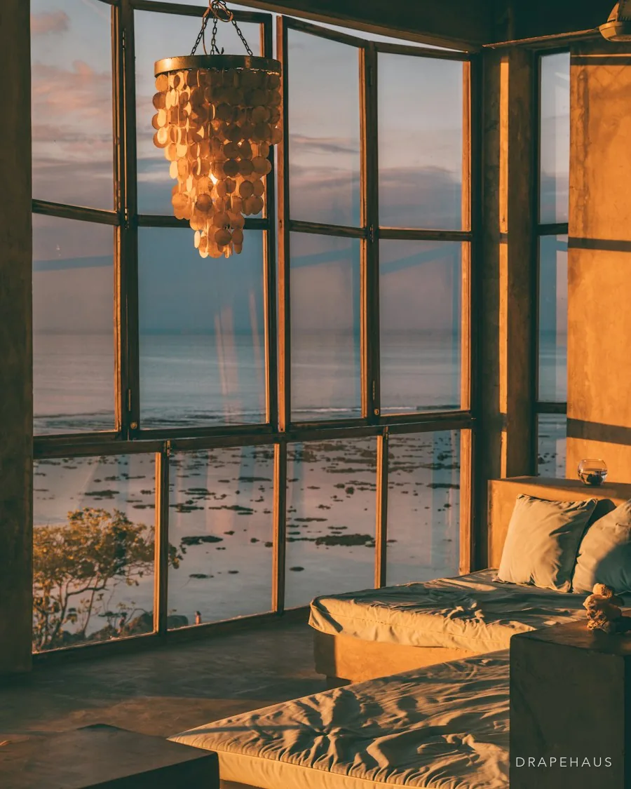 Tall glazing in a riverside home, with a low sun over the water