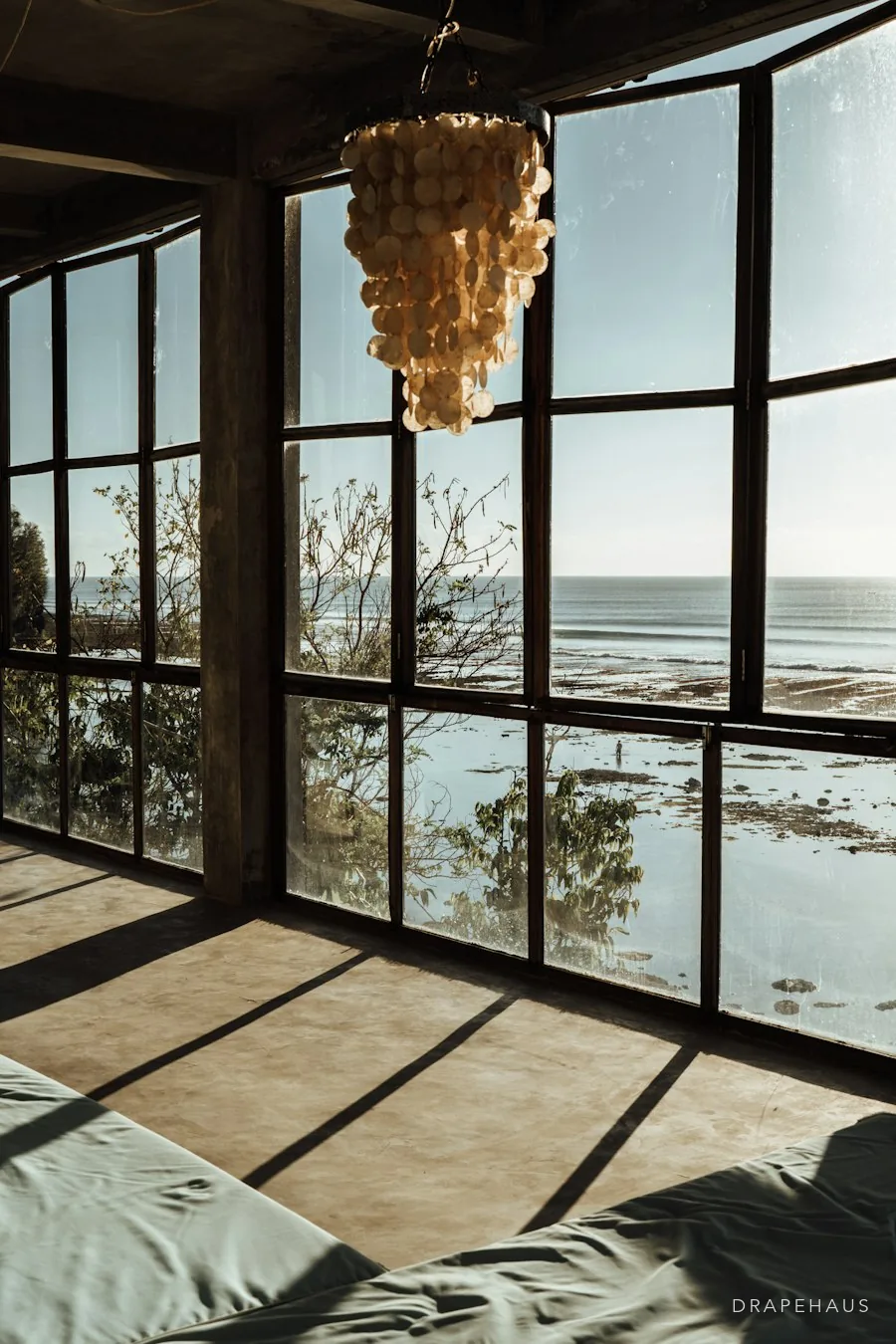 A sea-facing room with tall glazing and a low evening sun