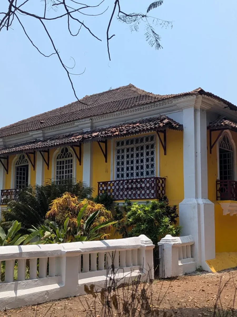 Long yellow facade of the Menezes Braganza House in Chandor, Salcete, with tiled roof and wooden balconies