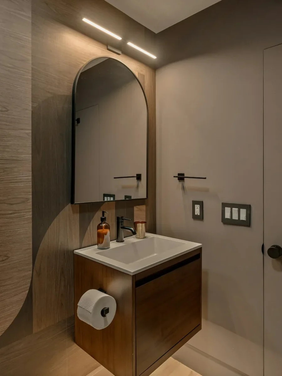 Small powder room with a large-scale wood-grain wallpaper, arched mirror and wall-hung vanity
