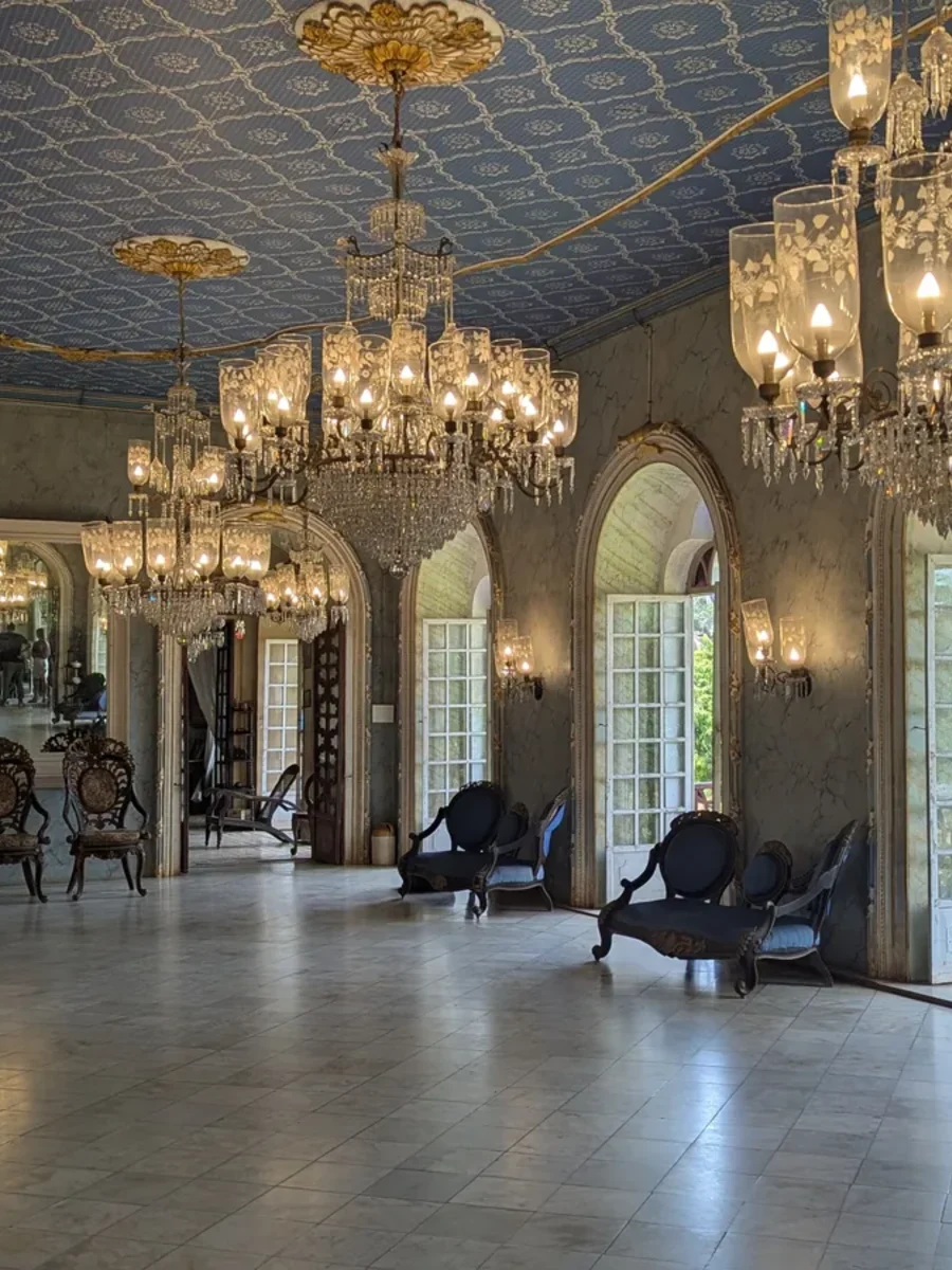 The ballroom of the Menezes Braganza House in Chandor, with crystal chandeliers and blue upholstered chairs