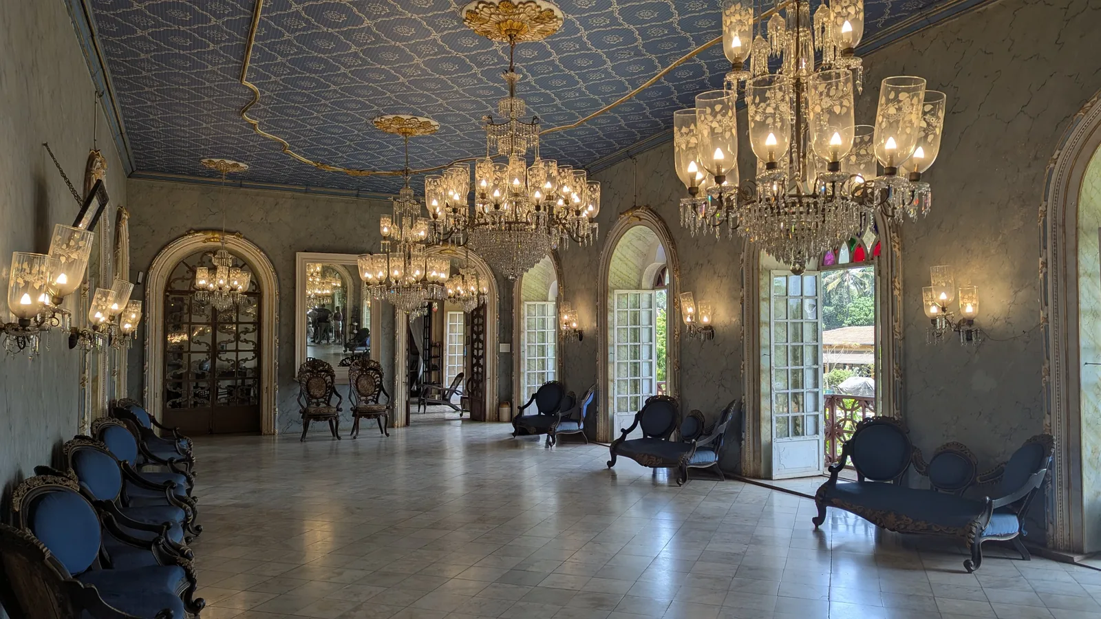 The ballroom of the Menezes Braganza House in Chandor, with crystal chandeliers and blue upholstered chairs