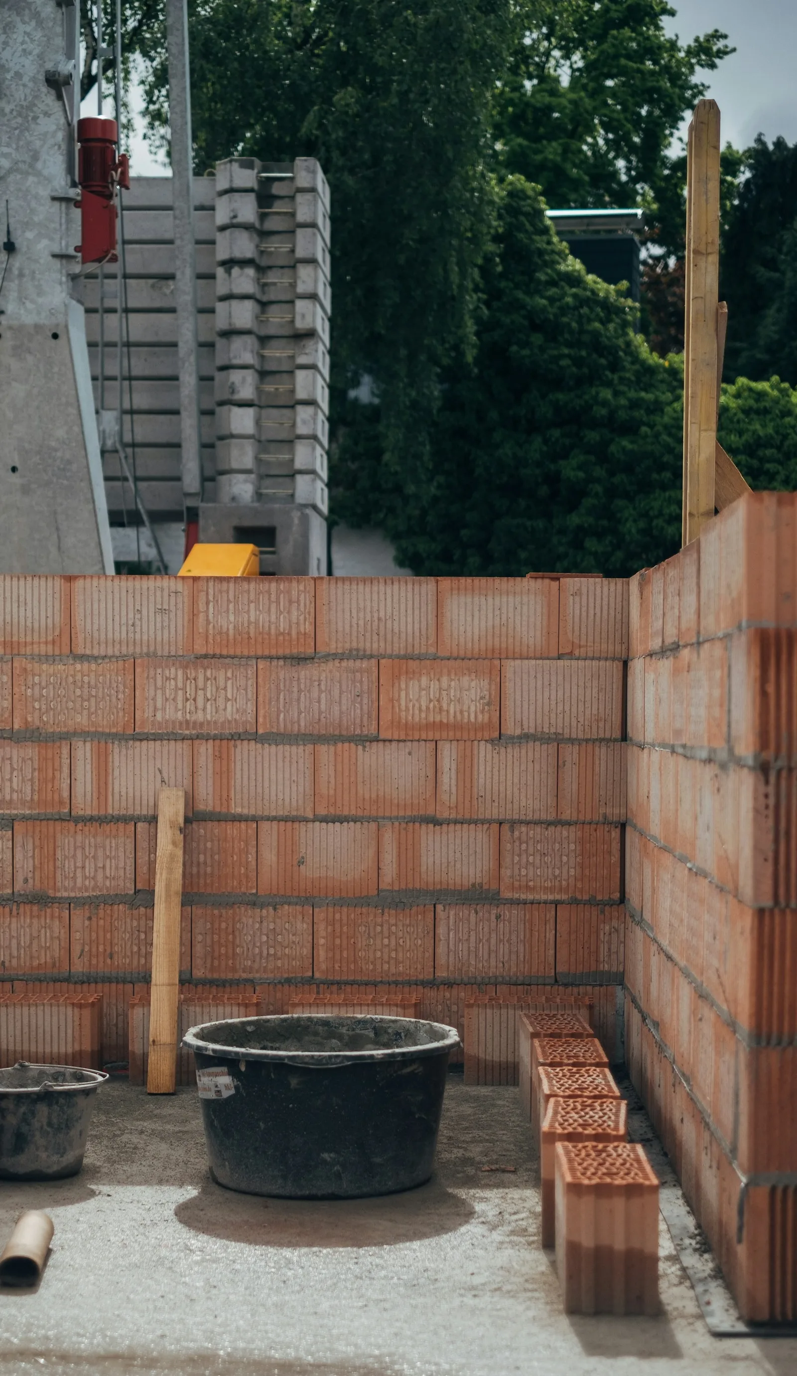 New clay block walls rising on a small building site with a mortar tub and timber props
