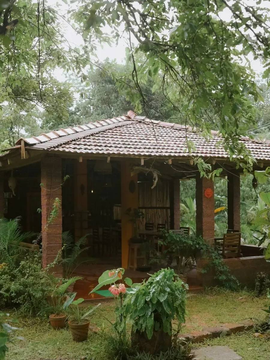 Traditional tiled-roof house with a laterite verandah set in a leafy garden in Valpoi, Goa
