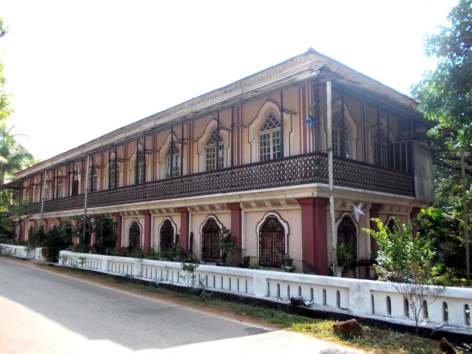 The long two-storey Casa Grande in Chandor with arched windows, a carved balcony and a white boundary wall