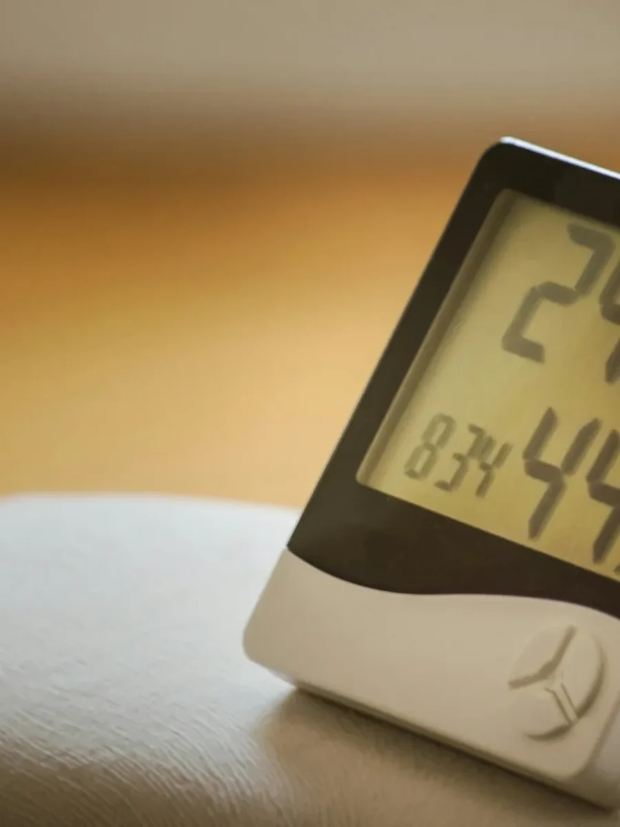 Digital hygrometer on a table showing room temperature and 44 percent relative humidity