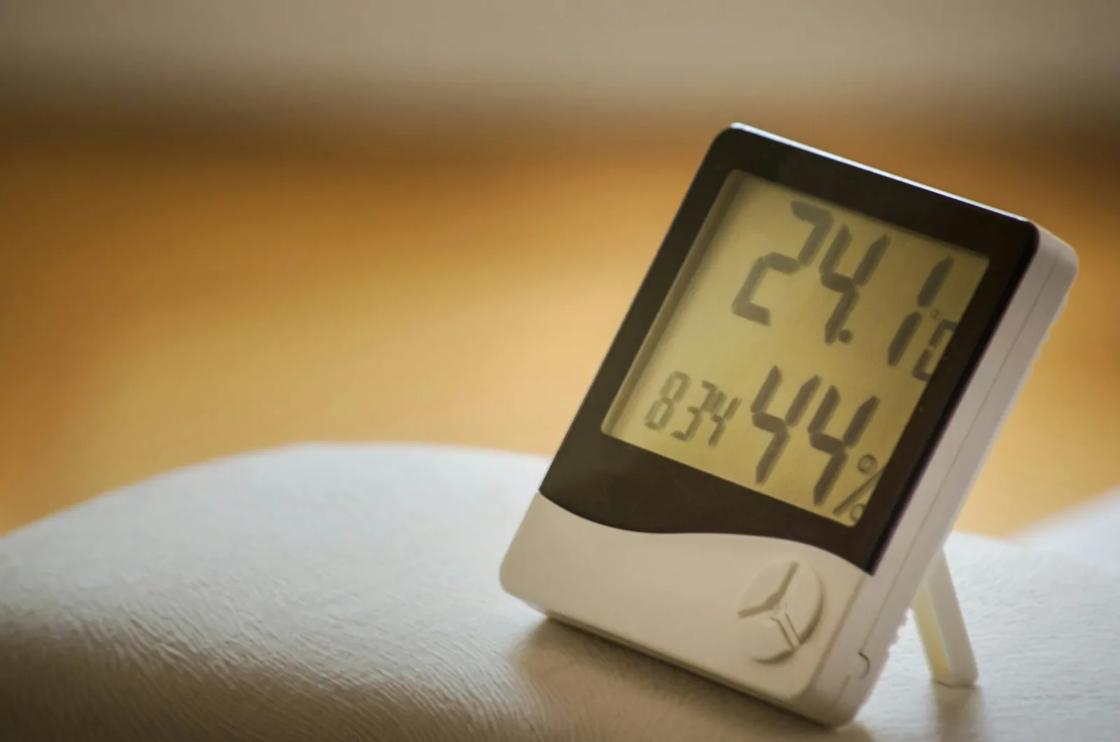 Digital hygrometer on a table showing room temperature and 44 percent relative humidity
