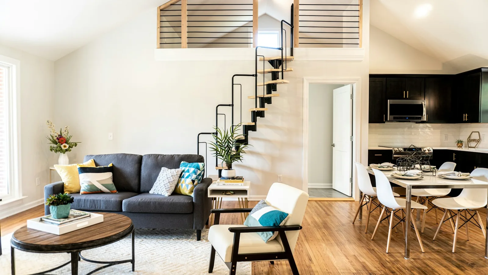 Double-height living room with a spiral stair rising to a loft gallery above the sofa