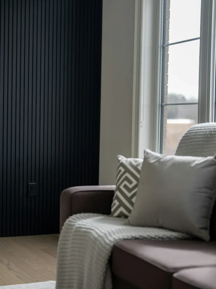 Black vertical fluted panel wall beside a marble fireplace surround and a brown sofa