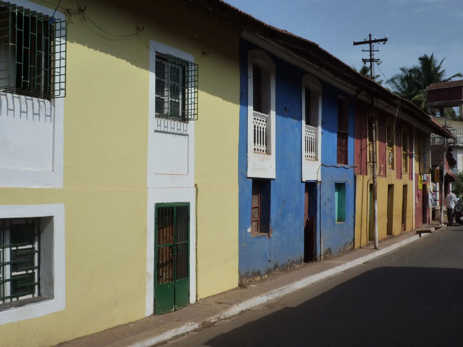 Yellow, blue and red lime-washed houses with shuttered windows lining a quiet street in Fontainhas, Panaji