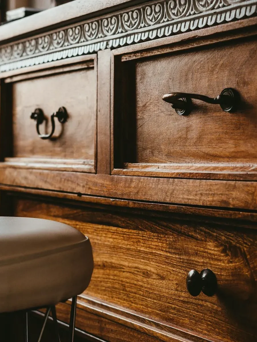 Close view of a carved dark wooden chest of drawers with metal handles