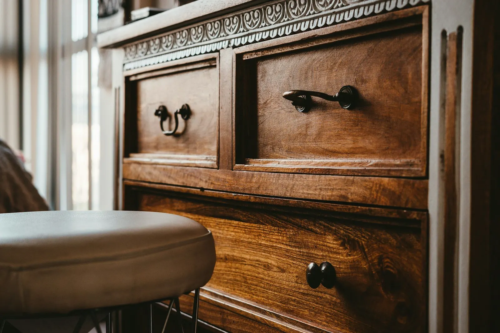 Close view of a carved dark wooden chest of drawers with metal handles