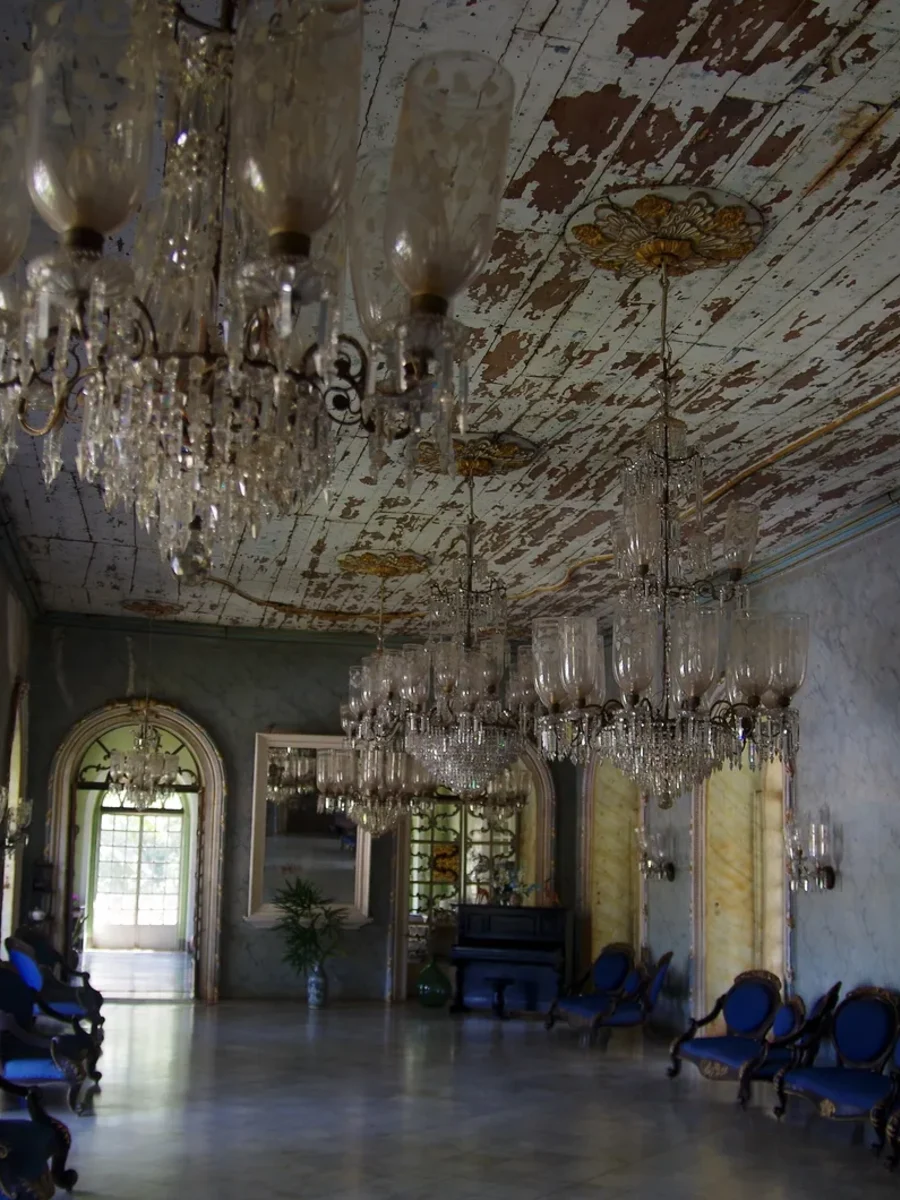 The ballroom of the Menezes Braganza house in Chandor, with crystal chandeliers, arched windows and blue chairs