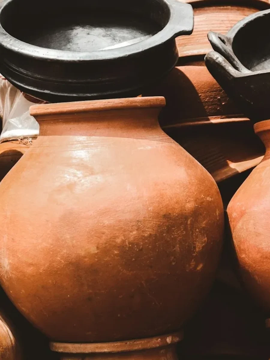 Stacked unglazed terracotta pots and black clay cooking vessels at a pottery stall in India