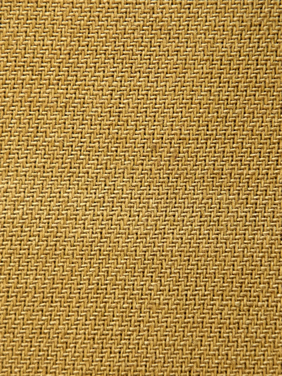 Close-up of a coarse golden woven natural-fibre surface, similar in texture to grasscloth