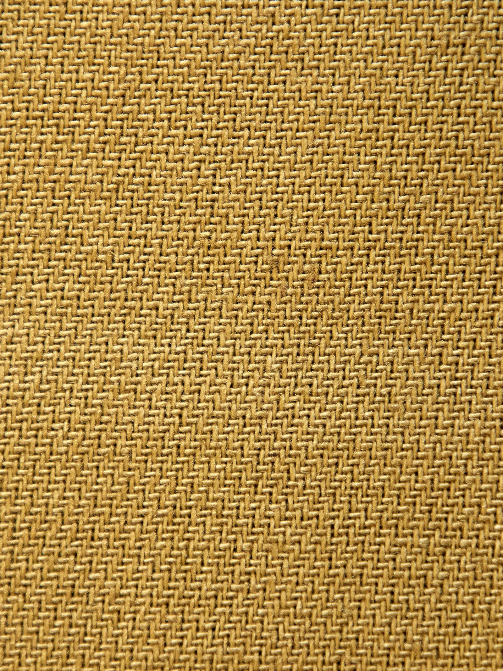 Close-up of a coarse golden woven natural-fibre surface, similar in texture to grasscloth