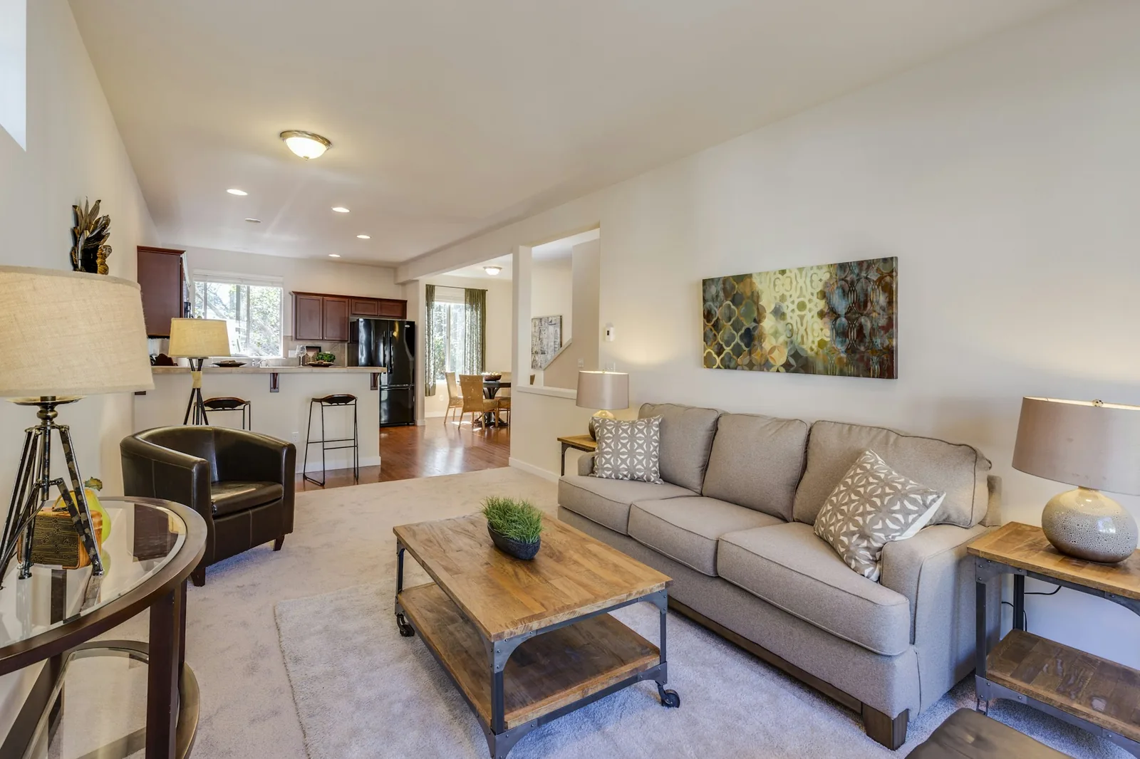 Open-plan living room with a grey sofa facing a leather armchair across a wooden coffee table