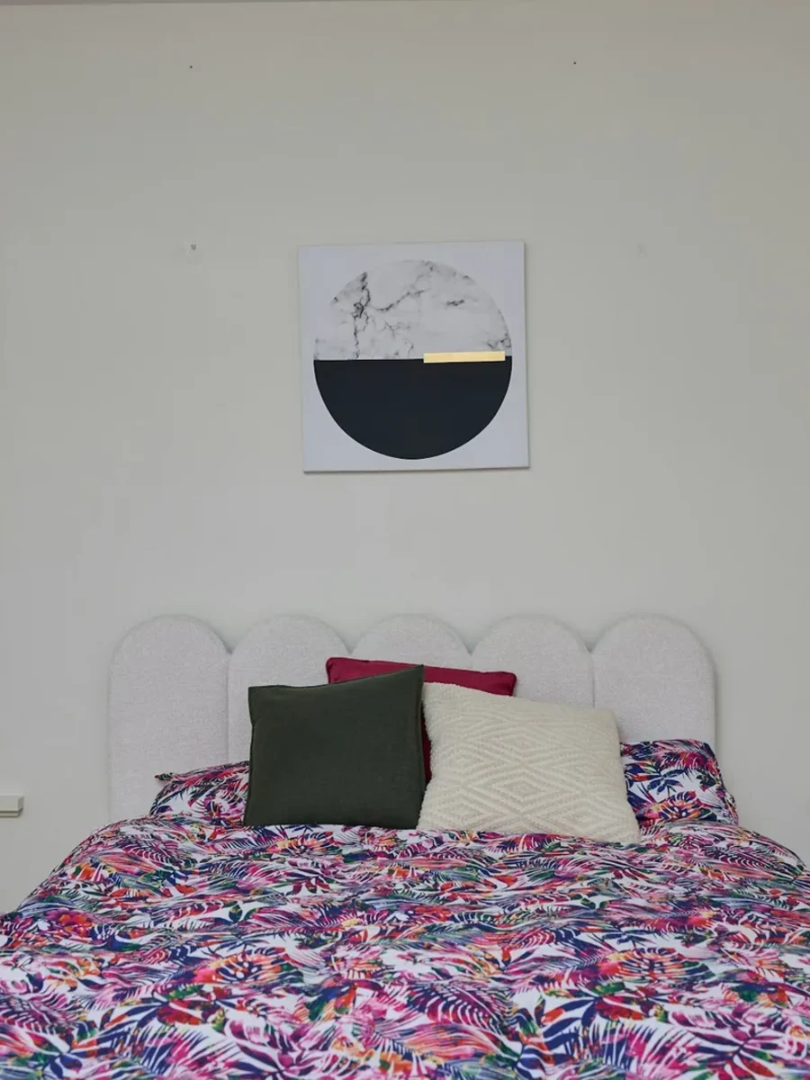 Two white fabric roller blinds pulled down on tall windows either side of a bed