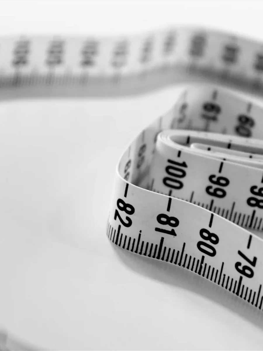 A cloth tape measure coiled loosely on a white surface, its centimetre markings in sharp focus