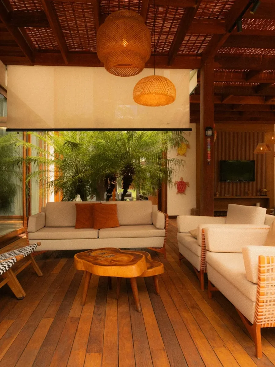 Covered timber-decked living veranda with white sofas, woven chairs, rattan lamps and a palm courtyard