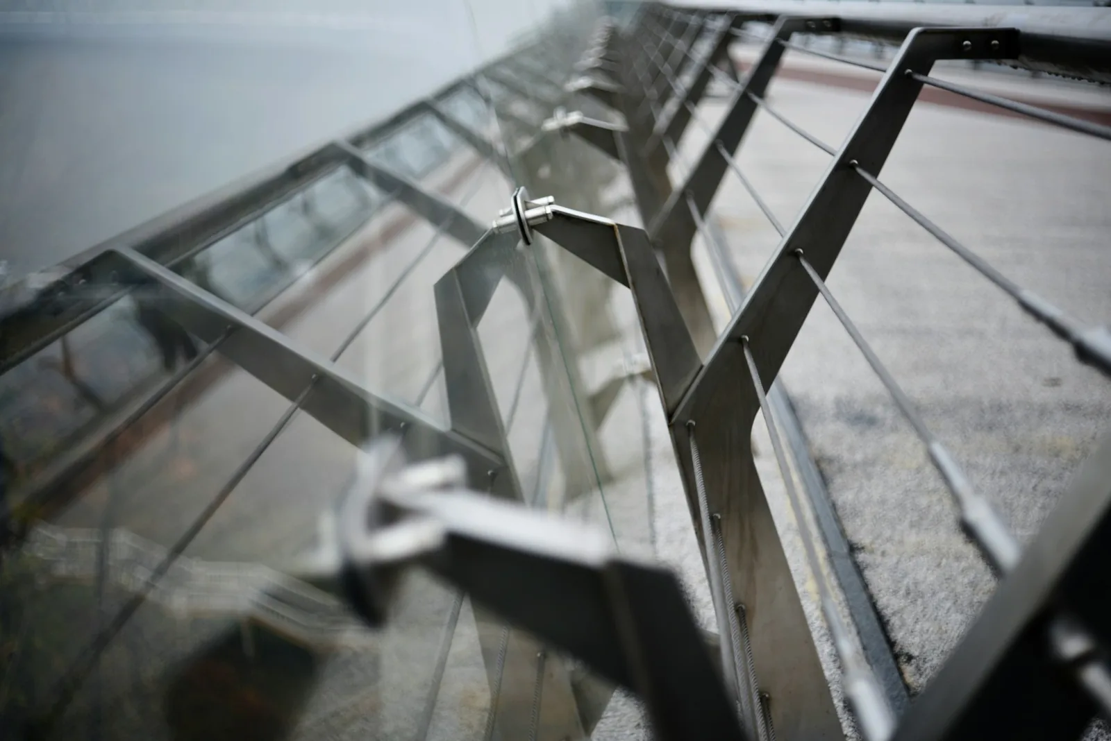 Close view of thin tensioned steel cables and angled posts on a glass-and-metal railing