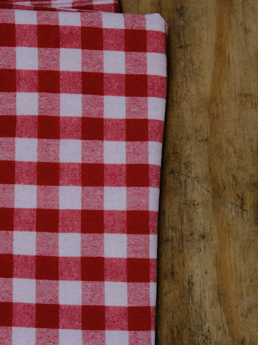 Folded red-and-white checked cotton cloth lying on a weathered wooden table