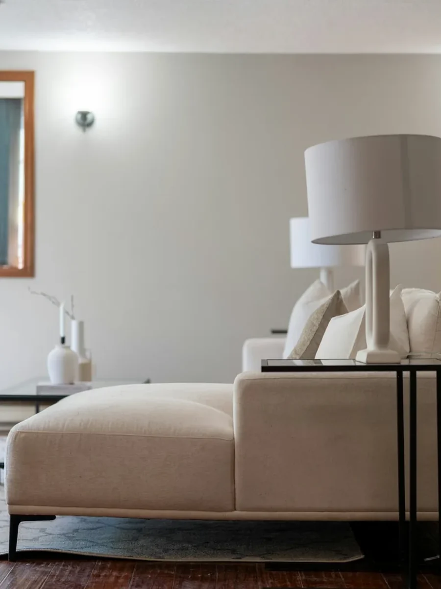 Cream chaise-ended lounge sofa with white lamps, glimpsed through a doorway into a living room